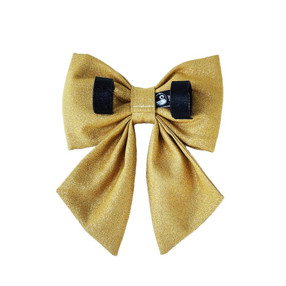 The back view of a sparkly bright gold dog bow with Velcro tapes to attach it to the collar.