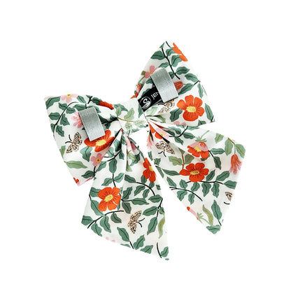The back view of a dog sailor bow with orange and pink flowers, green leaves and butterflies. The bow has Velcro tapes to attach it to the collar.