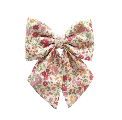 A dog collar bow for girls with a soft pink flower print on a creamy background.