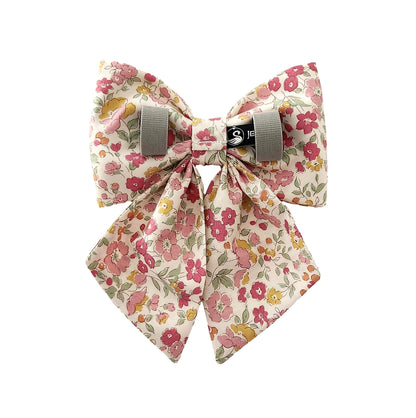 A back view of a dog sailor bow for girls in a sot pink floral print. The bow has Velcro tapes to attach it to the collar.