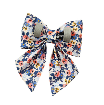 A back view of a dog sailor bow in a pink and blue floral print with Velcro tapes to attach to the collar.