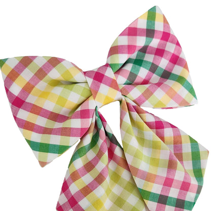 A close-up view of a plaid dog sailor bow for the collar in a pink, yellow, lime and green print. 