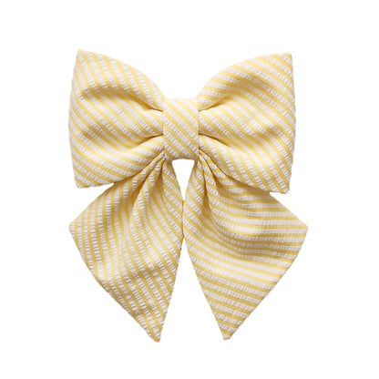 A yellow and white striped dog sailor bow for girls that attaches to the collar in seersucker fabric.