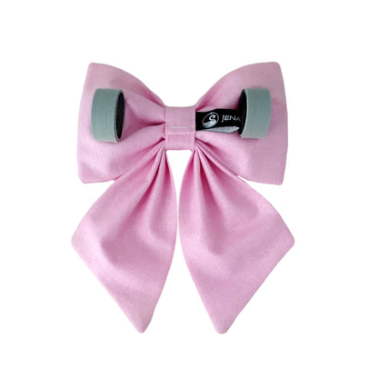 The back view of a pink glittery dog sailor bow with Velcro tapes to attach to the collar.