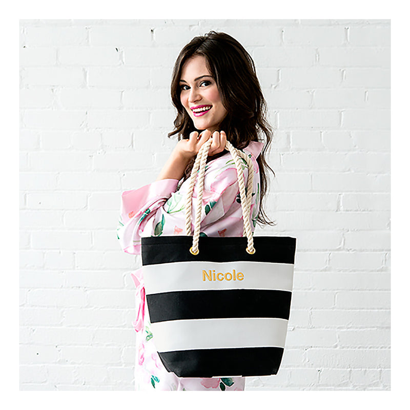 Model holding black and white stripe tote bag