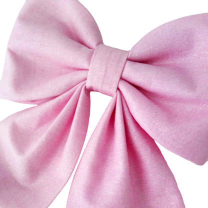 A close-up of a glittery pink dog bow for girls that attaches to the collar.